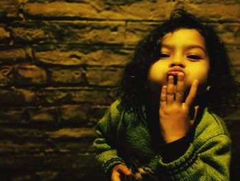 Close-up portrait of girl making face while standing against wall