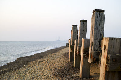 Wooden posts on beach against clear sky