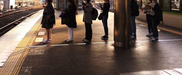 Low section of people walking on railroad station platform