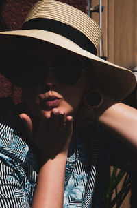 Portrait of woman wearing hat blowing a kiss outdoors