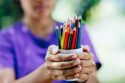 Midsection of girl holding colored pencils