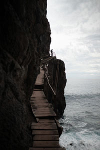 Low angle view of man standing on cliff by sea