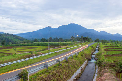 Road amidst field against sky