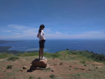 Woman on a rock with a view of the sea and blue sky