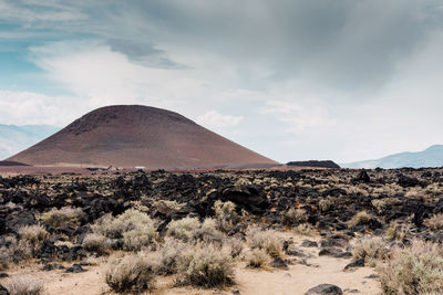 Scenic view of desert against cloudy sky