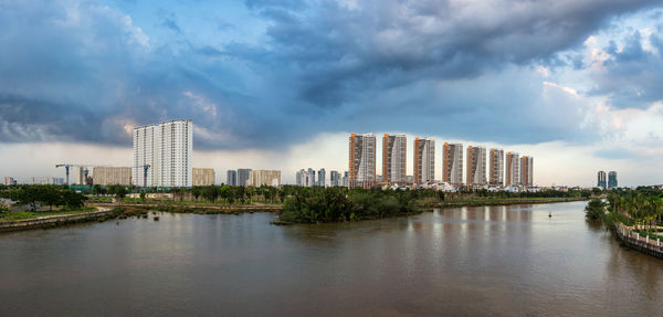 Buildings by river against sky in city