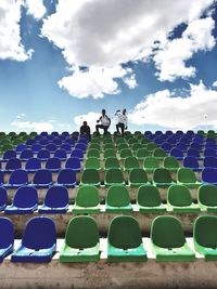 Low angle view of people on chairs against sky