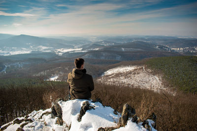 Rear view of man looking at mountain during winter