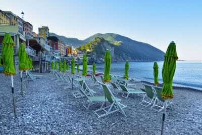 Chairs on beach against clear blue sky