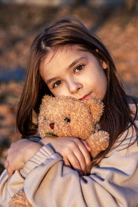 Girl hugging teddy bear and looking at camera
