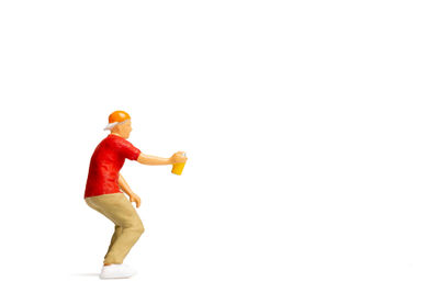 Side view of young man with toy standing against white background