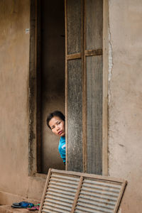 Portrait of smiling woman standing against window