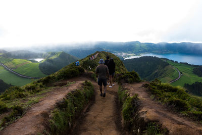 Rear view of man walking on road against mountain range