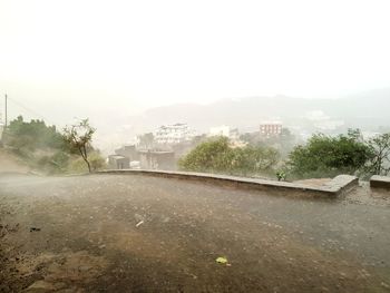 Buildings and trees against sky in foggy weather