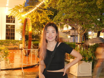 Portrait of smiling young woman standing against trees