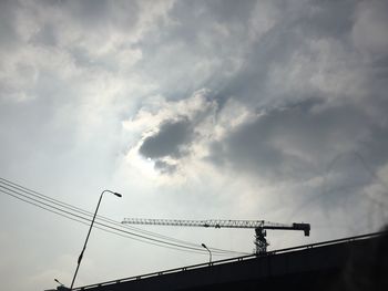 Low angle view of silhouette cables against sky