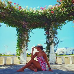 Woman wearing hat sitting at gazebo against sky