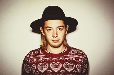 Portrait of confident man in hat against wall