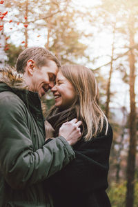 Happy couple and woman against trees during winter