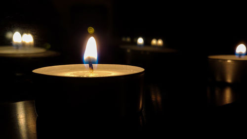 Close-up of lit candle in darkroom