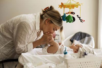 Side view of mother kissing son's feet at home