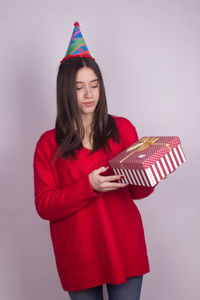 Beautiful young woman standing against red background