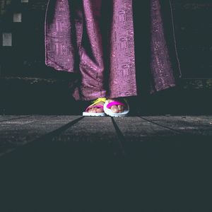 Low section of woman standing on multi colored umbrella