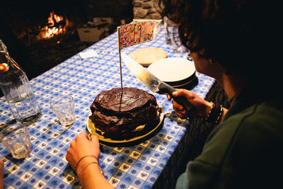 High angle view of young man cutting cake on table