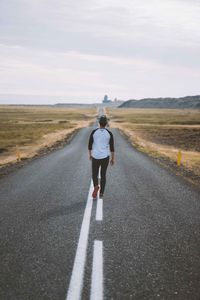 Full length and rear view of man standing on road