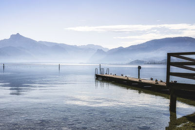 Pier on lake by snowcapped mountains against sky