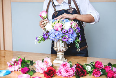 Midsection of florist arranging flowers in urn