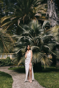 Full length of woman standing by palm trees