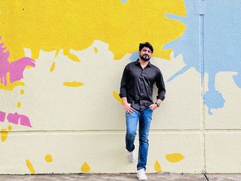 Portrait of young man standing against wall