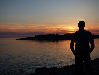 Silhouette man standing on beach against sky during sunset