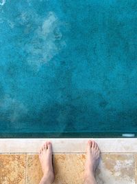 Low section of man standing in swimming pool