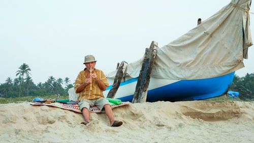 Man sitting on land against clear sky