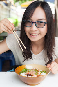 Close-up portrait of smiling young woman eating food