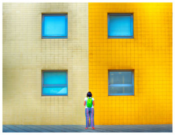 Full length of woman standing against yellow building