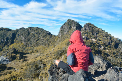 Low section of woman sitting on rock against sky