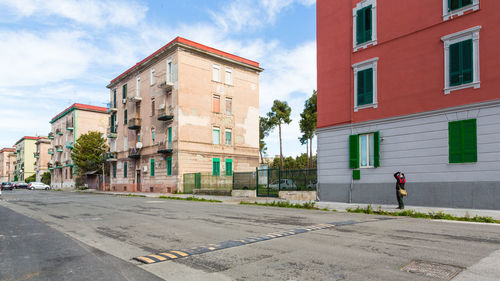 Road by buildings in city against sky