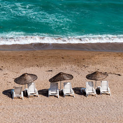 Three sunbed and umbrellas on the beach with clear blue sea, holiday, tourism and summer theme