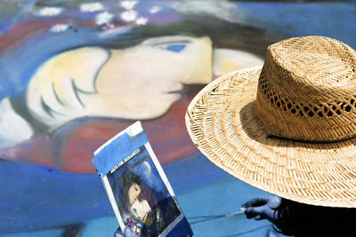 Close-up of person wearing hat against painting