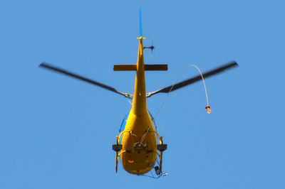 Low angle view of helicopter against blue sky