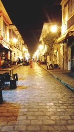 Illuminated street amidst buildings in city at night