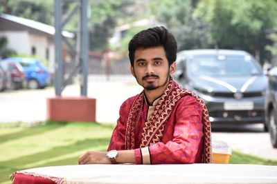 A handsome traditional boy sitting behind the table.