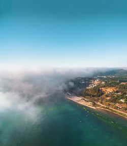Aerial view of sea against clear blue sky and some fog