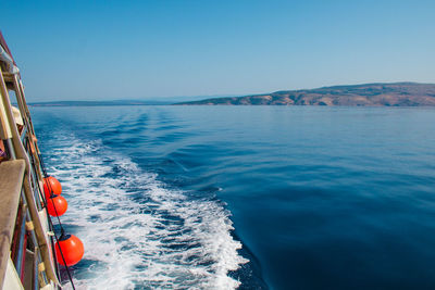 Sailboat sailing in sea against clear blue sky