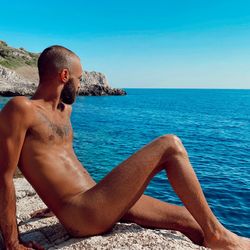 Midsection of shirtless man in sea against clear sky