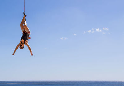 Woman hanging over sea against sky
