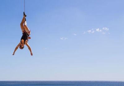 Man jumping in sea against sky